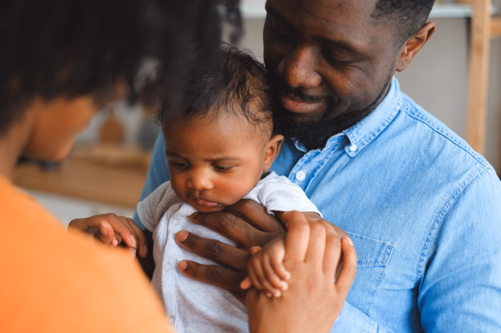 A caregiver resting while holding their baby, highlighting the importance of parental self‑care
