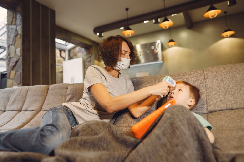 A caregiver using a digital thermometer on a child's forehead for safe monitoring