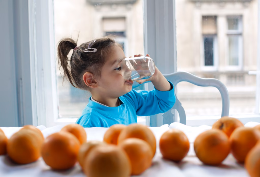 A child sipping water, highlighting the importance of hydration during a fever
