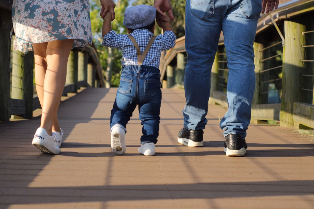 A child taking small supported steps with a caregiver’s hand