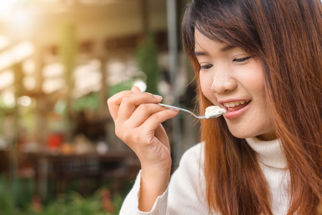 A person examining a bowl of yogurt, representing probiotic‑rich foods that may affect digestion."