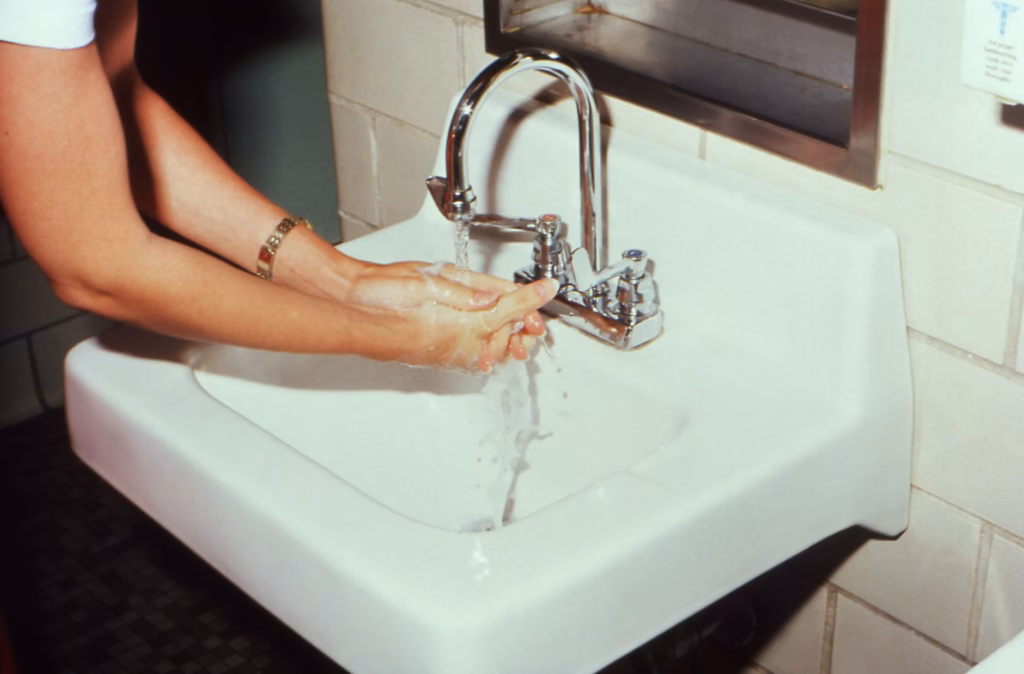 A person washing hands at a sink, illustrating proper hand hygiene