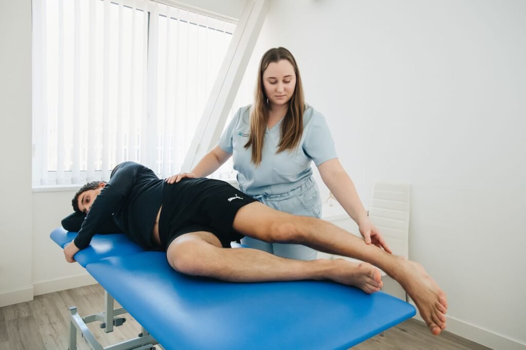 A physiotherapist assesses a patient’s leg after a strain