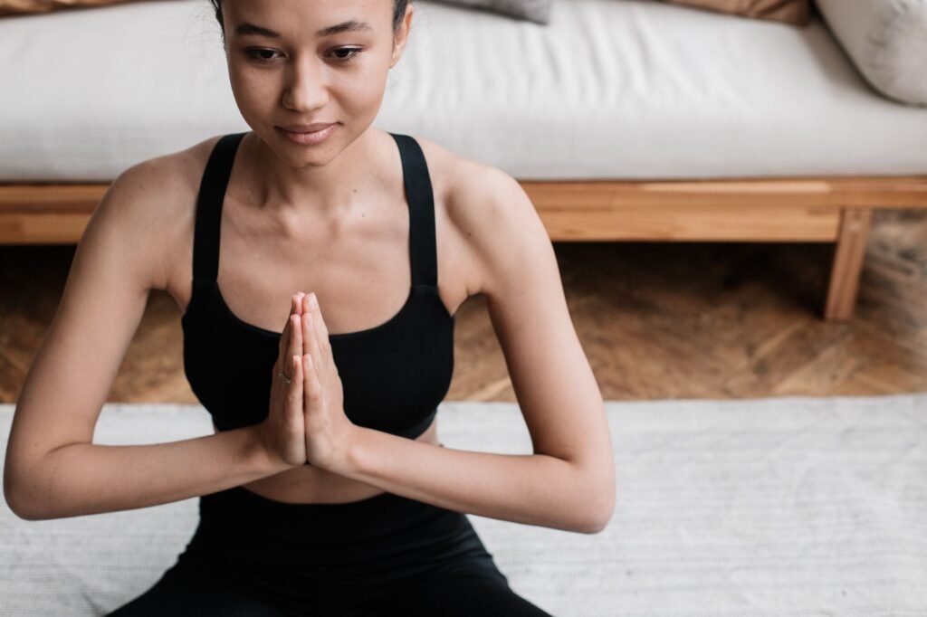 A woman in activewear meditating indoors, embodying peace and relaxation