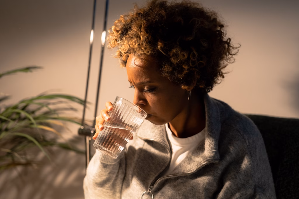 A woman sipping water to stay hydrated, an easy habit that supports regular bowel movements