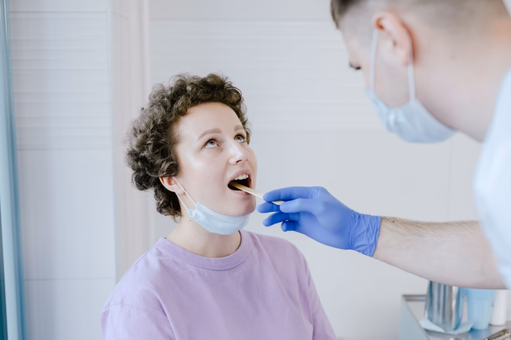 Nurse practitioner checking the throat for erythema and exudate